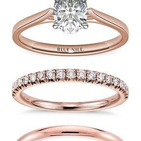 A stack of rings, a rose engagement ring and three wedding bands, two with diamonds, one without.